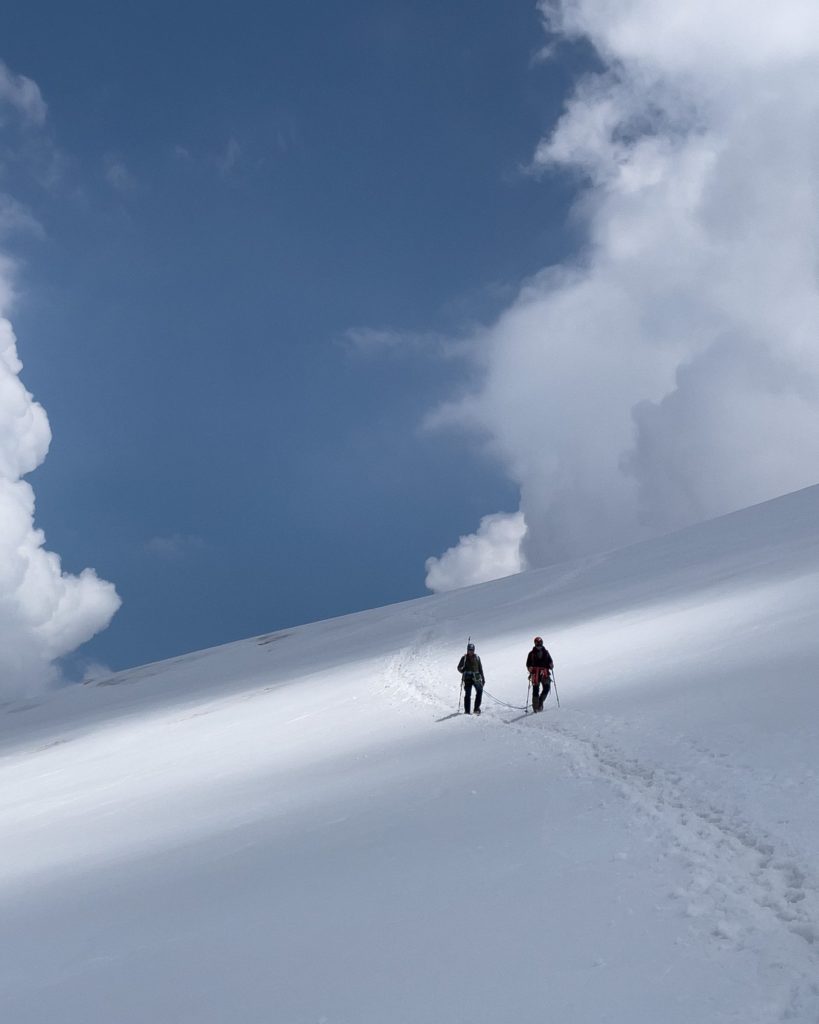 Two hikers on a snow covered mountain on a sunny day