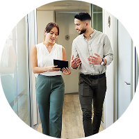 Two colleagues walking in office hallway, discussing work