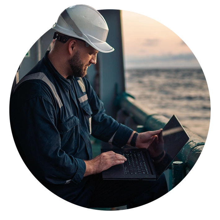 Engineer in hard hat using laptop on ship